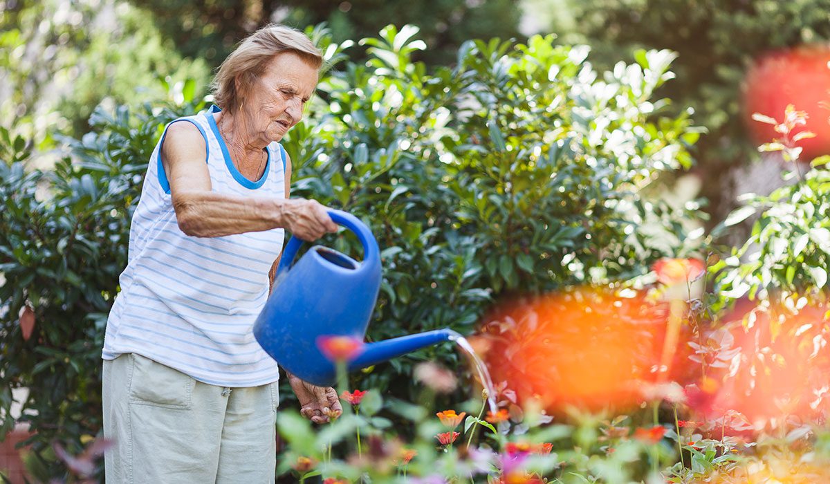 elderly woman watering garden