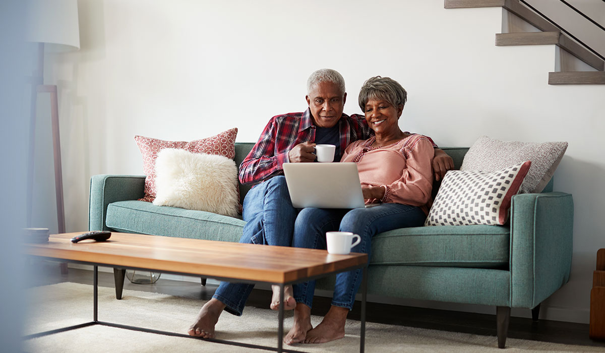 african-american-senior-husband-and-wife-on-couch-using-laptop